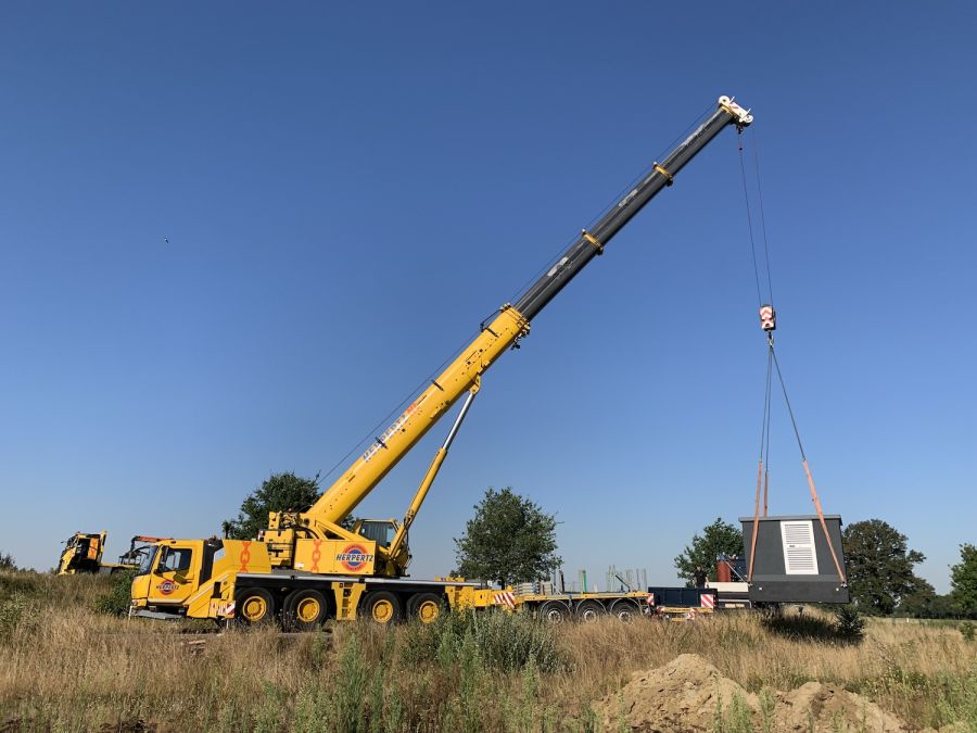 Hijskraan verplaatst transformator station op locatie waar zonnepark Reuver gebouwd wordt